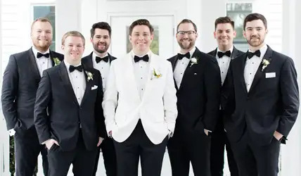 Groom in white tuxedo and out of town groomsmen in black tuxedos